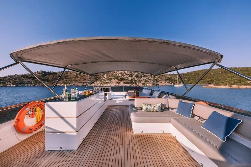 a large lounge area with a bar and a large building with a body of water in the background aboard OXYGEN 8 Yacht for Charter