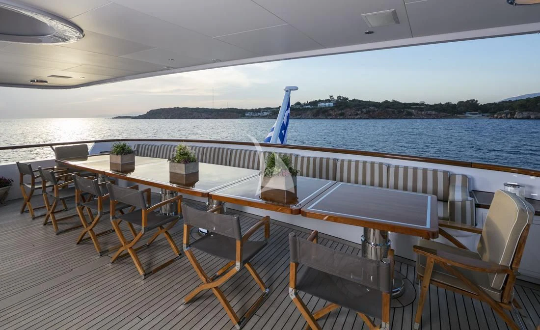 a table with chairs on it next to a body of water aboard PEGASUS Yacht for Charter