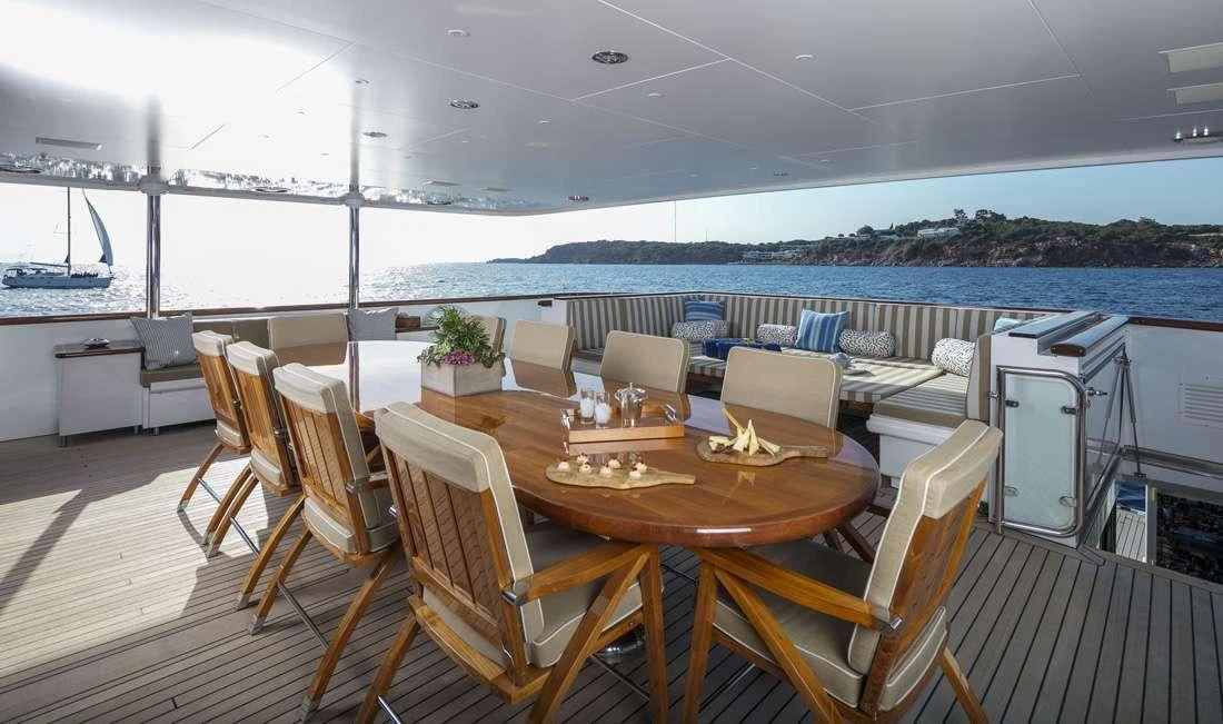 a large dining table with chairs and a large body of water in the background aboard PEGASUS Yacht for Charter