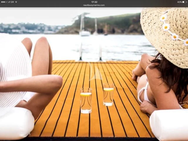 a woman sitting at a table with a glass of wine and a view of a body of water aboard PEGASUS Yacht for Charter