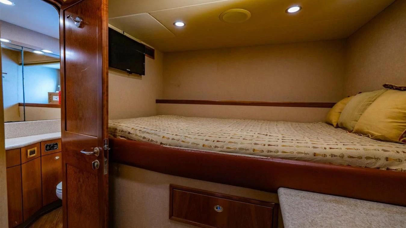 a bed with a television on the wall aboard SNOWBORED Yacht for Sale
