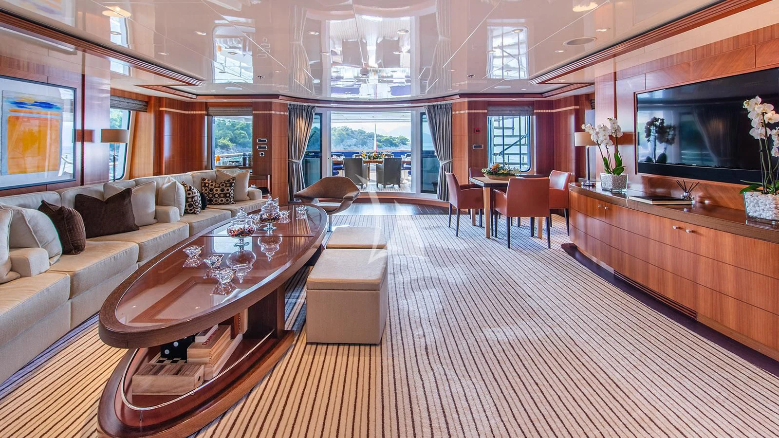 a living room with a large wood table and a large television aboard RARE FIND Yacht for Charter