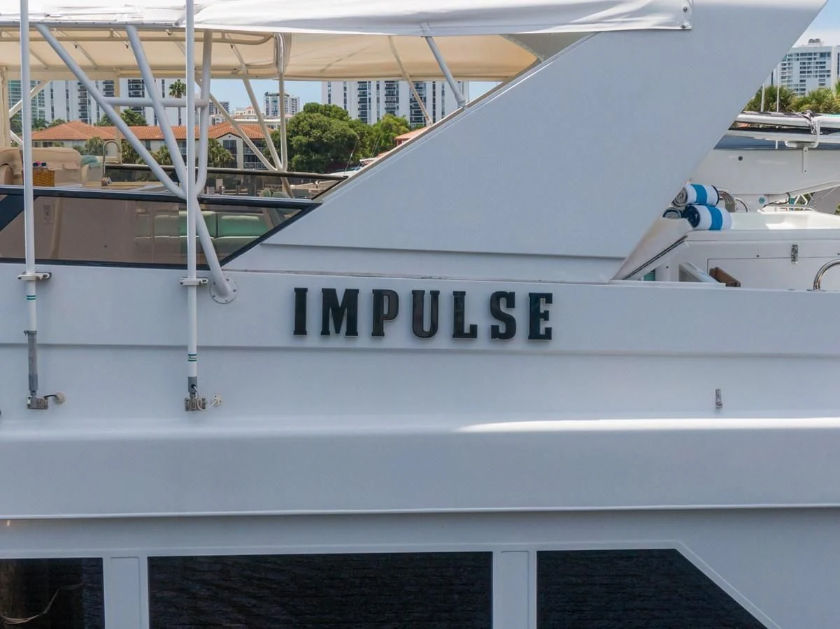 a white boat with a sign on the front aboard IMPULSE Yacht for Sale