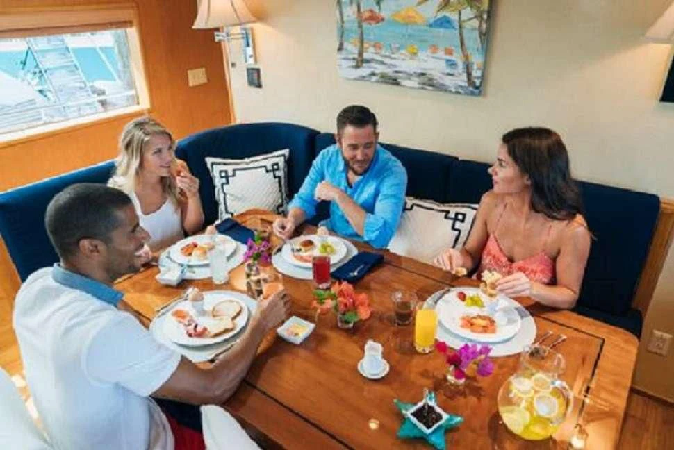 a group of people sitting around a table eating aboard IMPULSE Yacht for Sale