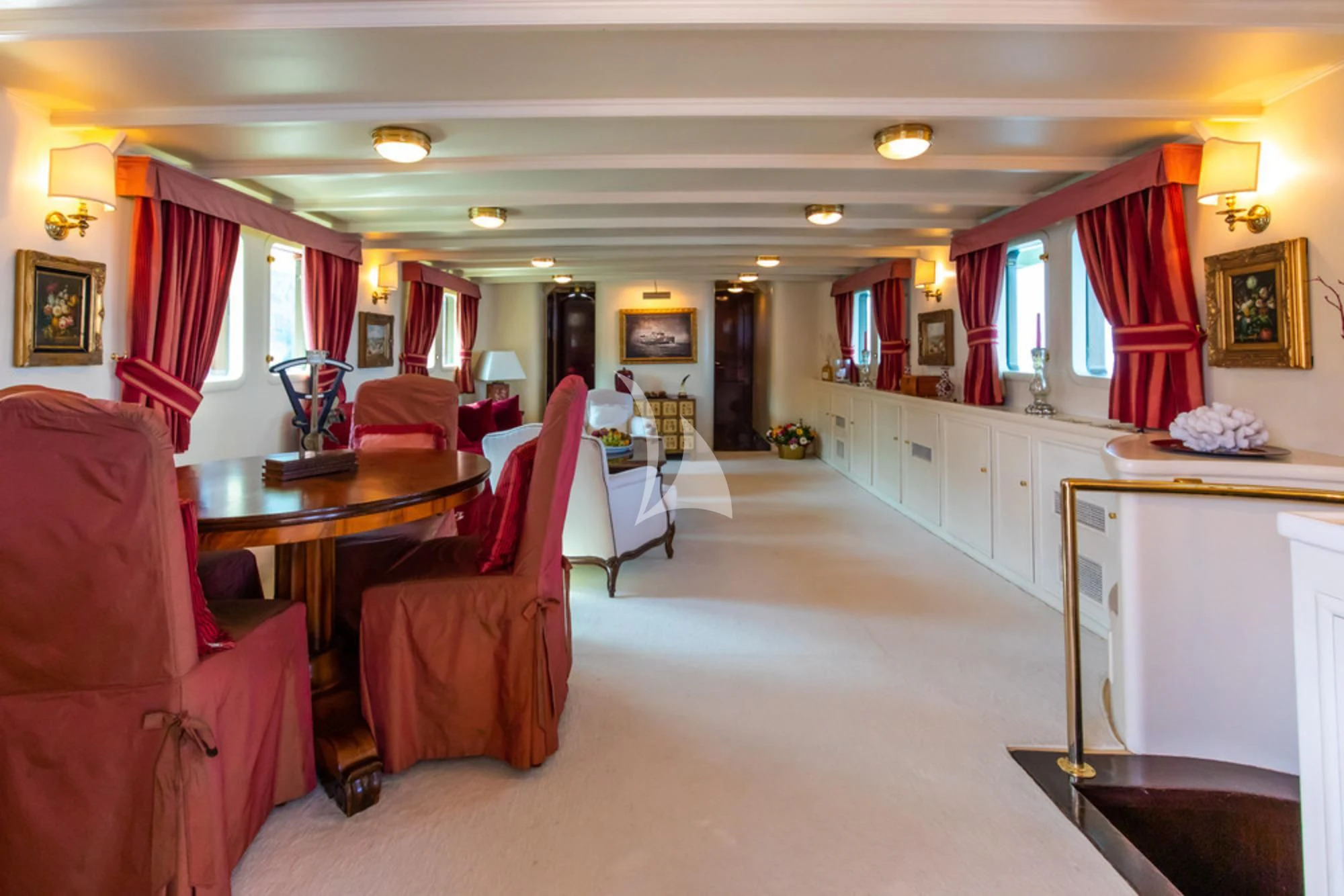 a large living room with red curtains aboard D.P. MONITOR Yacht for Sale