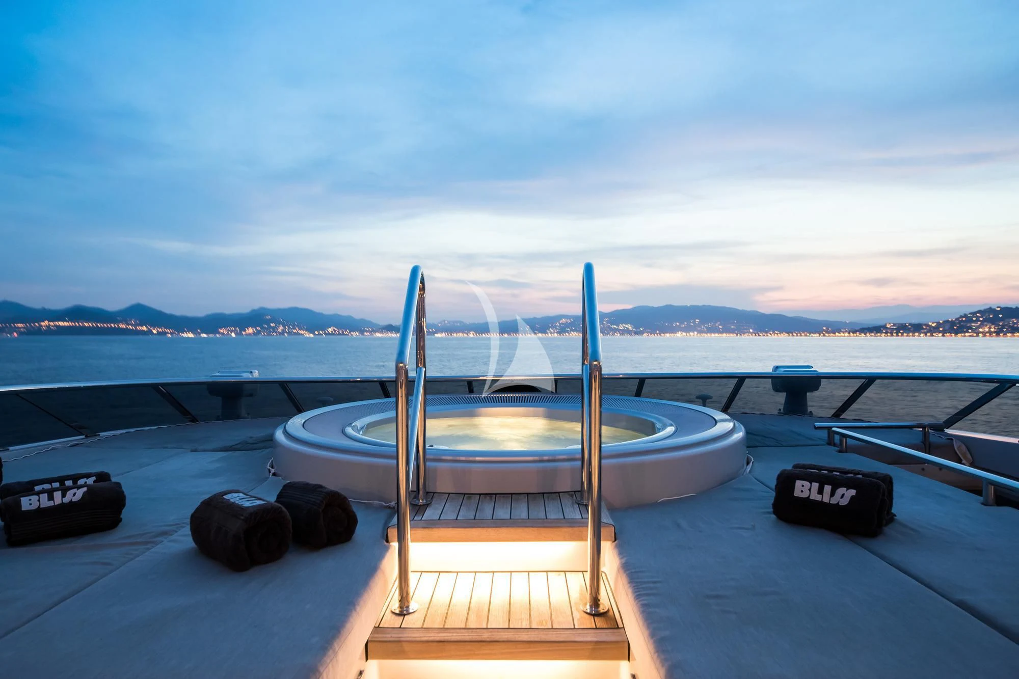 a deck with a pool and a view of water and mountains in the background aboard BLISS Yacht for Sale