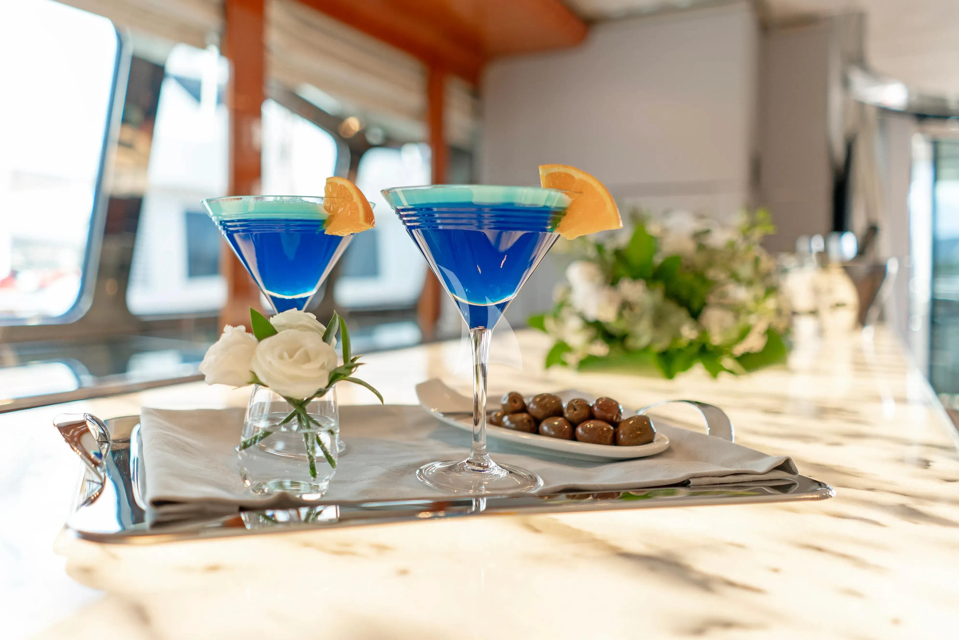 a table with a glass of blue liquid and a flower on it aboard BLISS Yacht for Sale