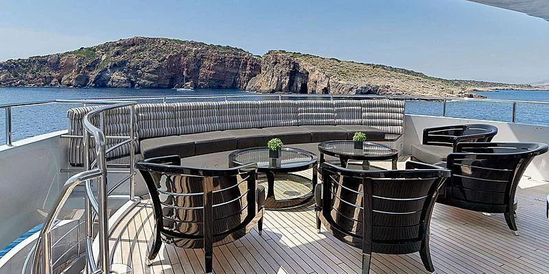 a patio with a table and chairs on it by the water aboard BLISS Yacht for Sale