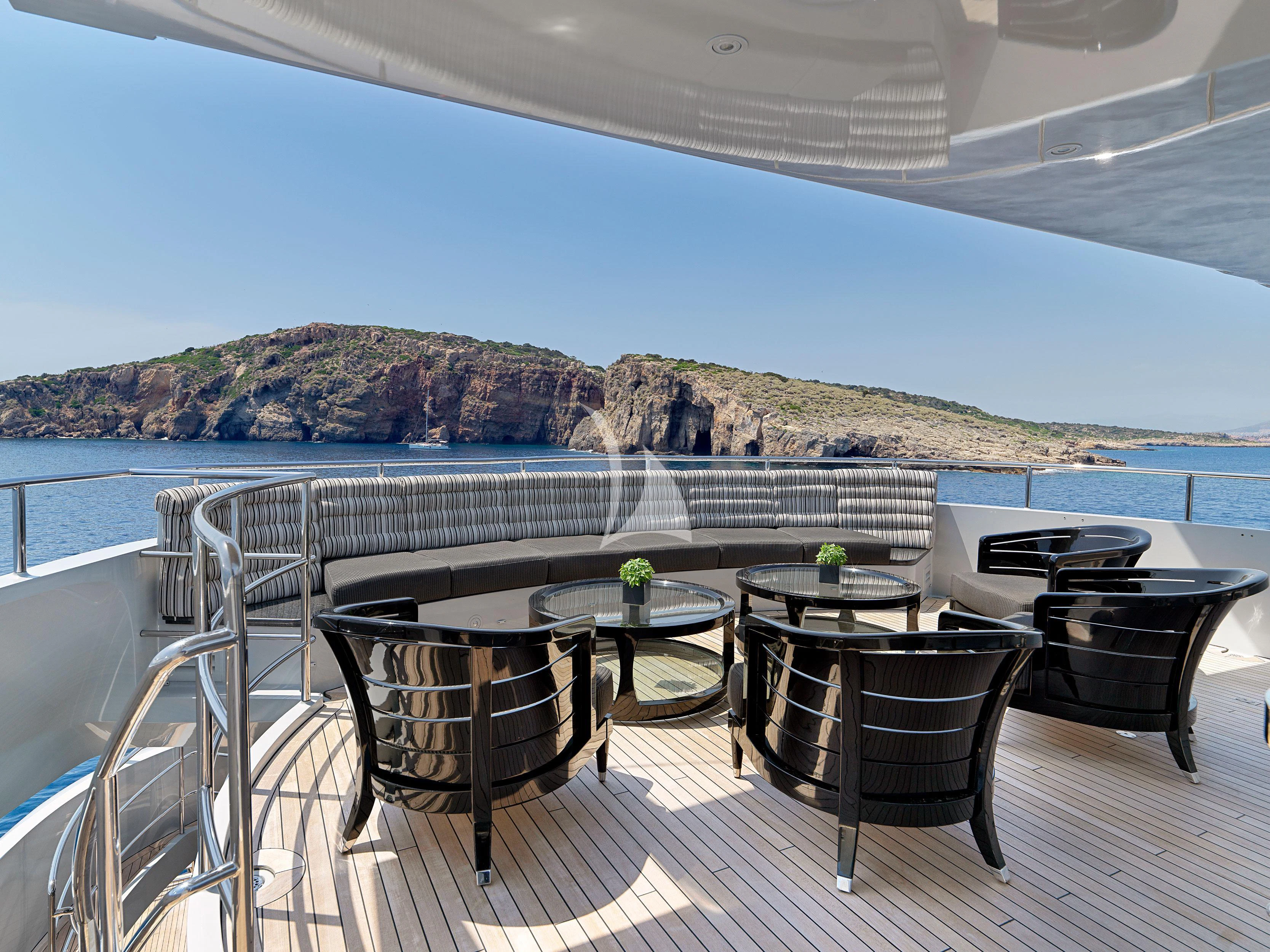 a table and chairs on a balcony overlooking a body of water aboard BLISS Yacht for Sale