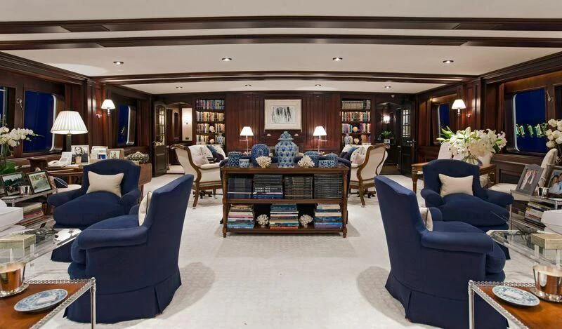 a large room with a blue chair and a table with chairs aboard VIRGINIAN Yacht for Sale