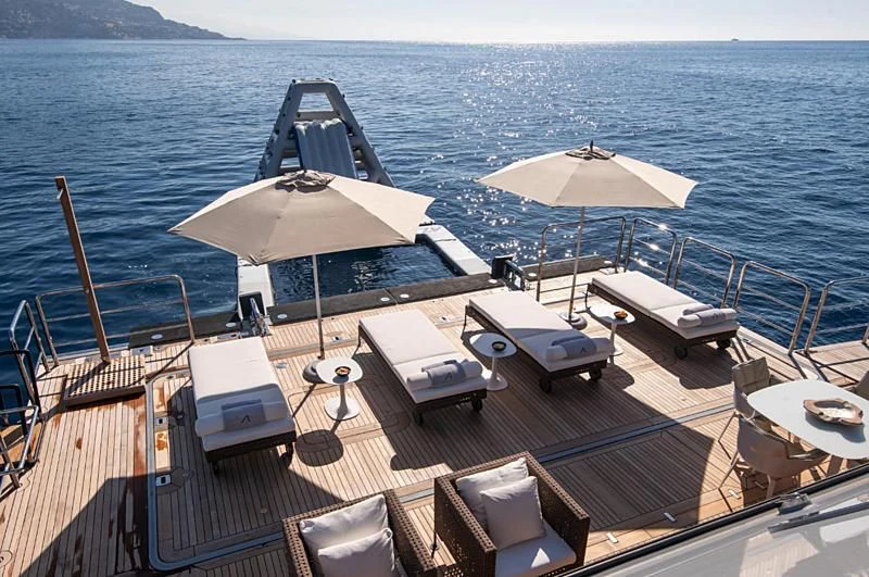 a deck with chairs and umbrellas on it by the water aboard ARBEMA Yacht for Sale