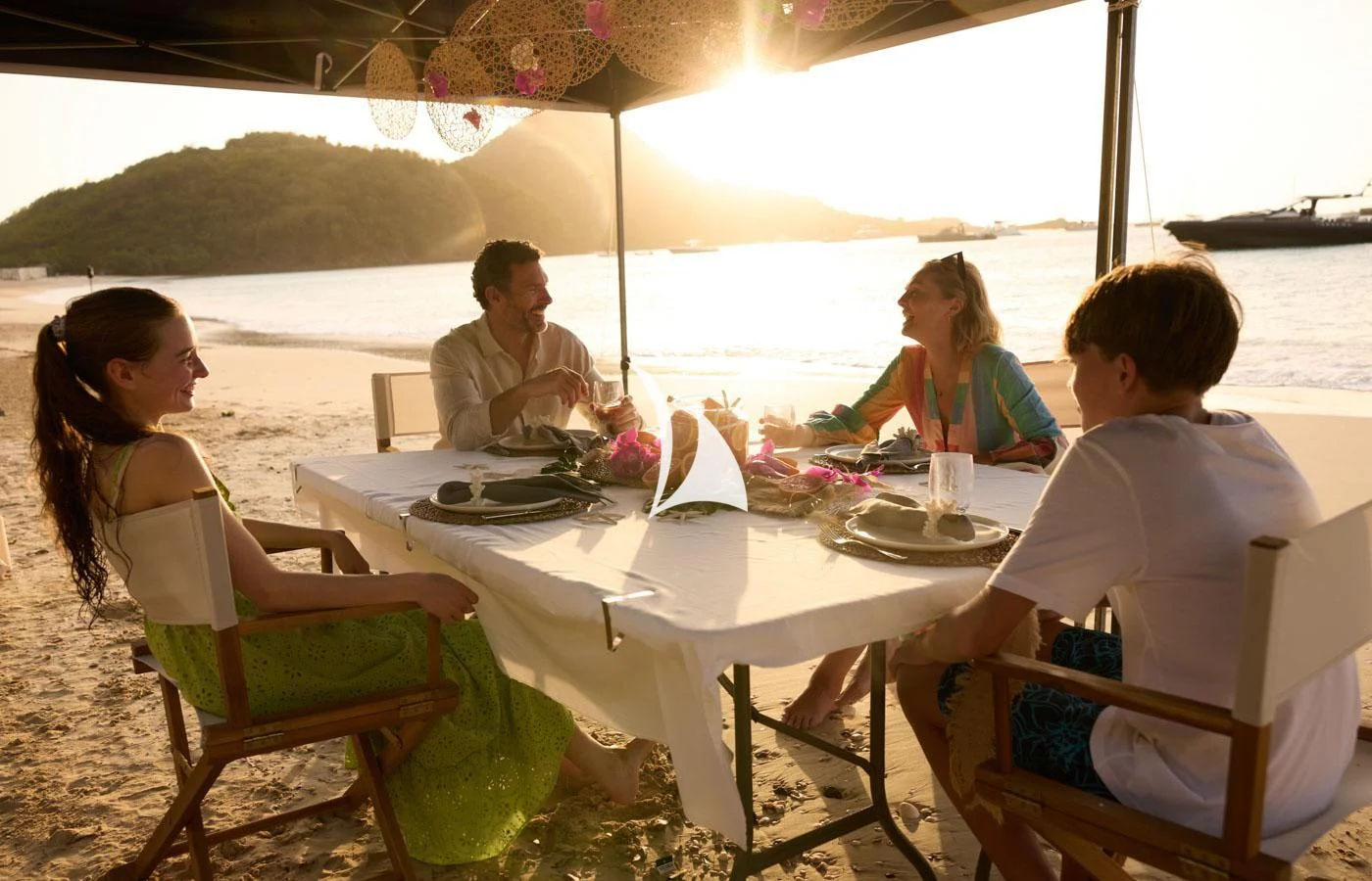 a group of people sitting around a table on a beach aboard ARBEMA Yacht for Sale