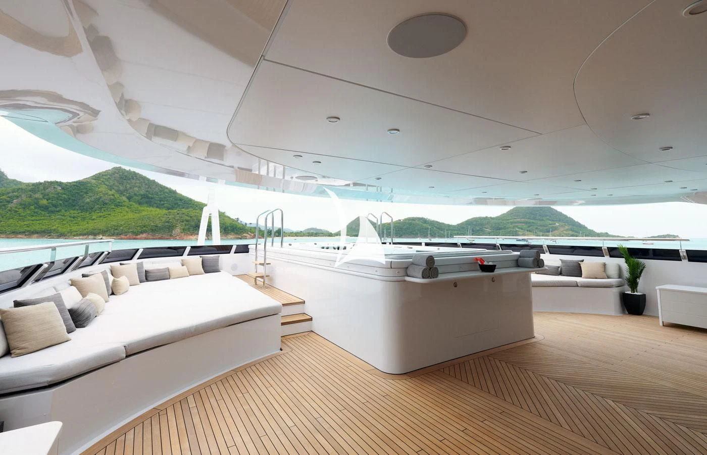 a room with a large white sofa and a large window with a view of the ocean and mountains aboard ARBEMA Yacht for Sale