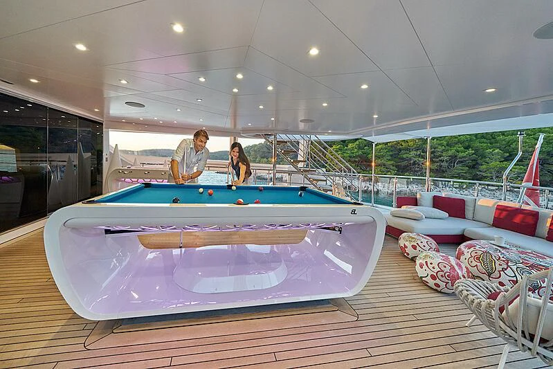 a couple of people sitting at a pool table aboard HAPPY ME Yacht for Charter