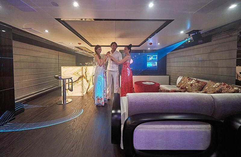 a man and woman standing in a room with a couch and a television aboard HAPPY ME Yacht for Charter