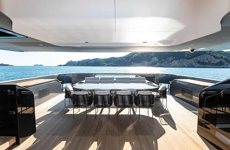 a room with a table and chairs on a deck overlooking a large body of water aboard PANAM Yacht for Sale