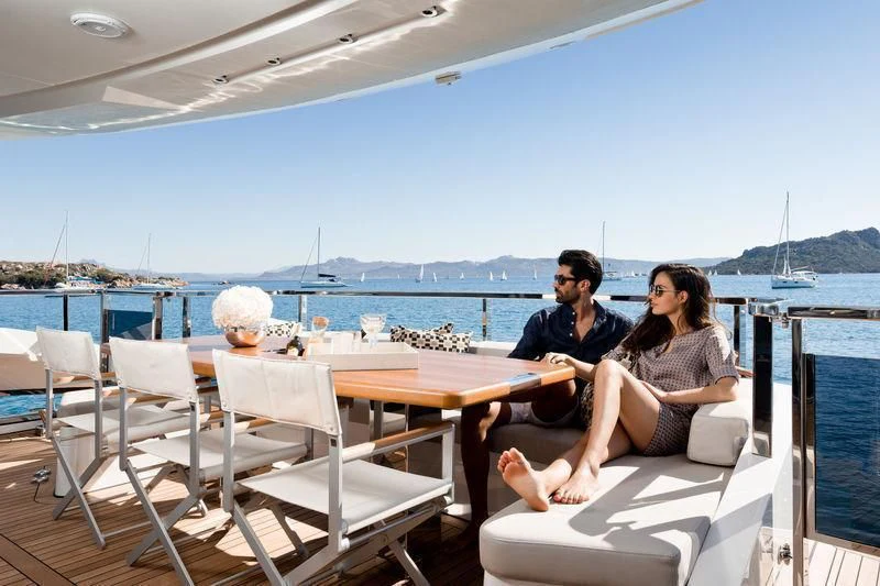 a man and woman sitting on a boat with a woman sitting on the deck and looking at the aboard MAXIMUS Yacht for Sale