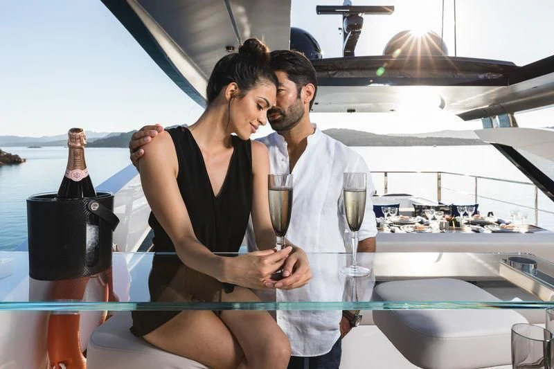 a man and a woman looking at a bottle of wine aboard MAXIMUS Yacht for Sale