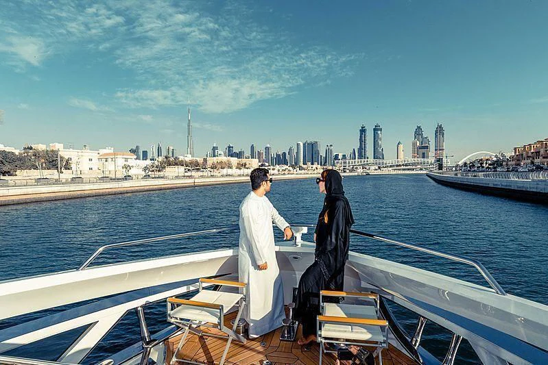 a man and woman sitting on a boat with a city in the background aboard MAXIMUS Yacht for Sale