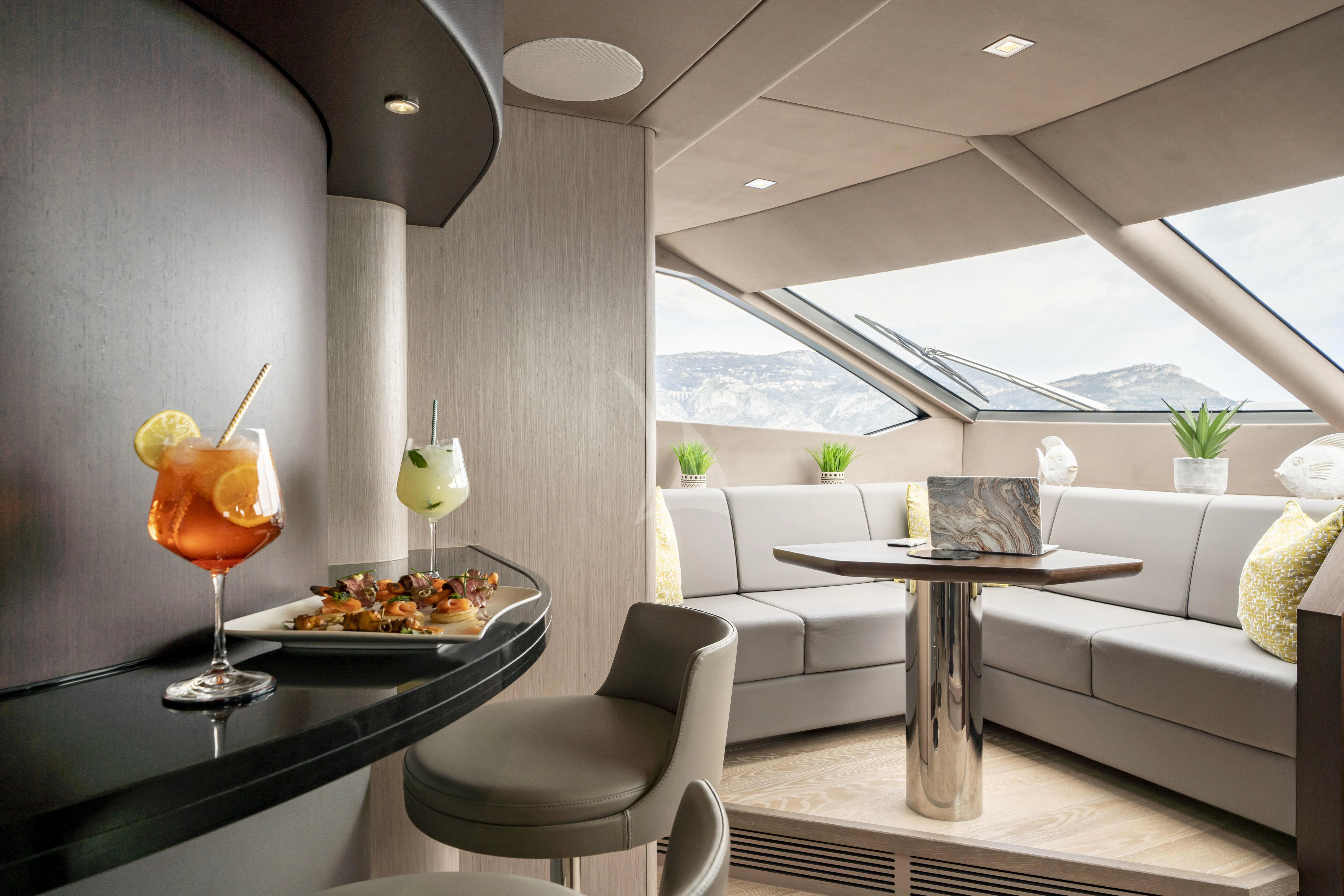 a modern living room with a glass of orange juice and a large window aboard TORO Yacht for Sale
