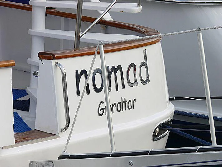 a white boat with a sign on it aboard NOMAD Yacht for Sale