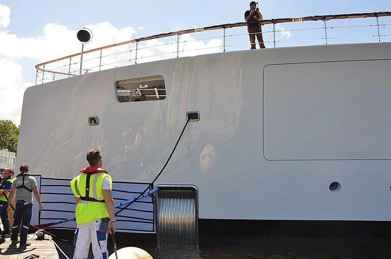 a group of people standing next to a large boat aboard 818 Yacht for Sale