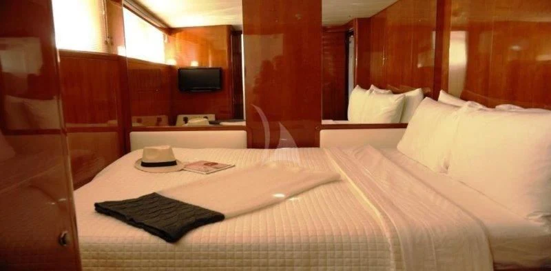 a bed with a white sheet and black hat on it aboard MOONRAKER II Yacht for Sale