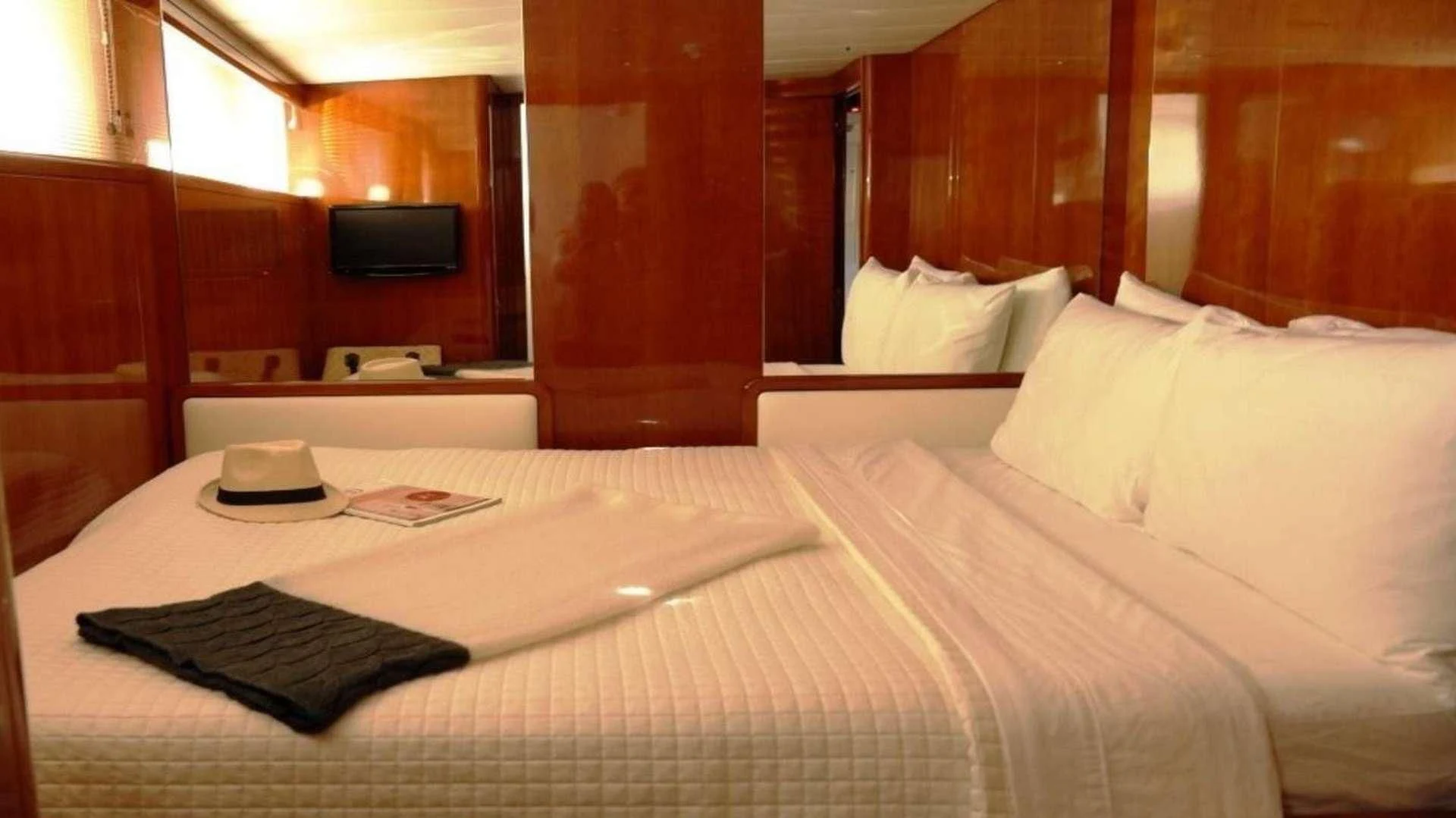 a bed with a white sheet and black hat on it aboard MOONRAKER II Yacht for Sale