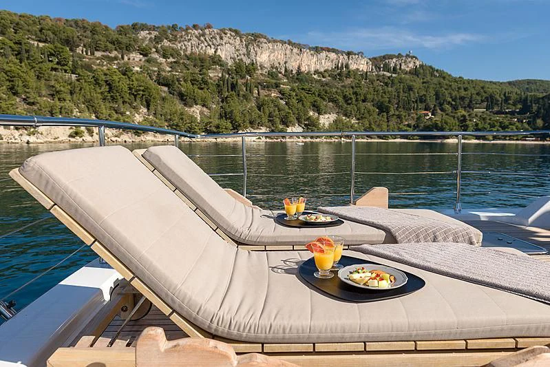 a white lounge chair on a balcony overlooking a body of water aboard MOONRAKER II Yacht for Sale
