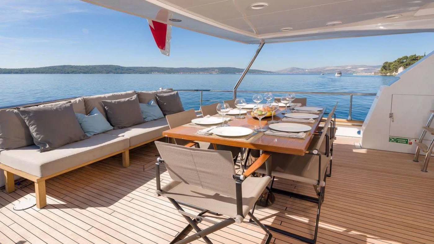 a table and chairs on a deck overlooking a body of water aboard MOONRAKER II Yacht for Sale