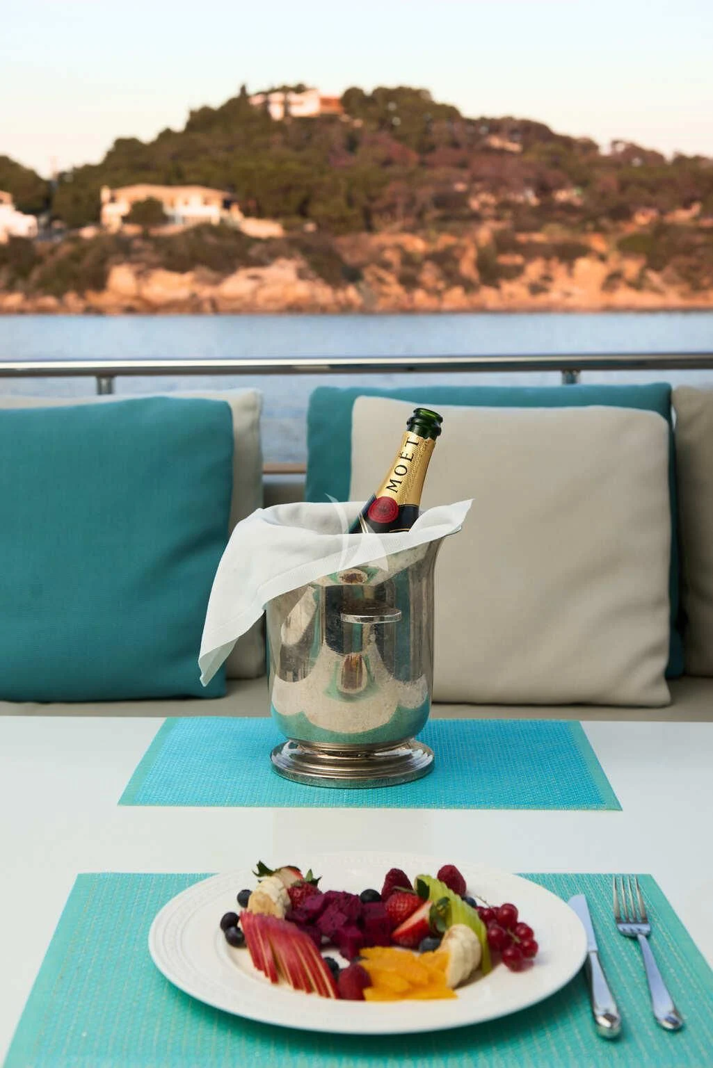 a bottle of champagne on a table with a plate of food and a glass of water aboard DE ZEUS Yacht for Sale