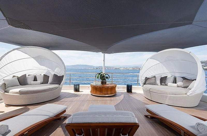 a room with a large white bed and a round table with a plant on it aboard NENINKA Yacht for Sale
