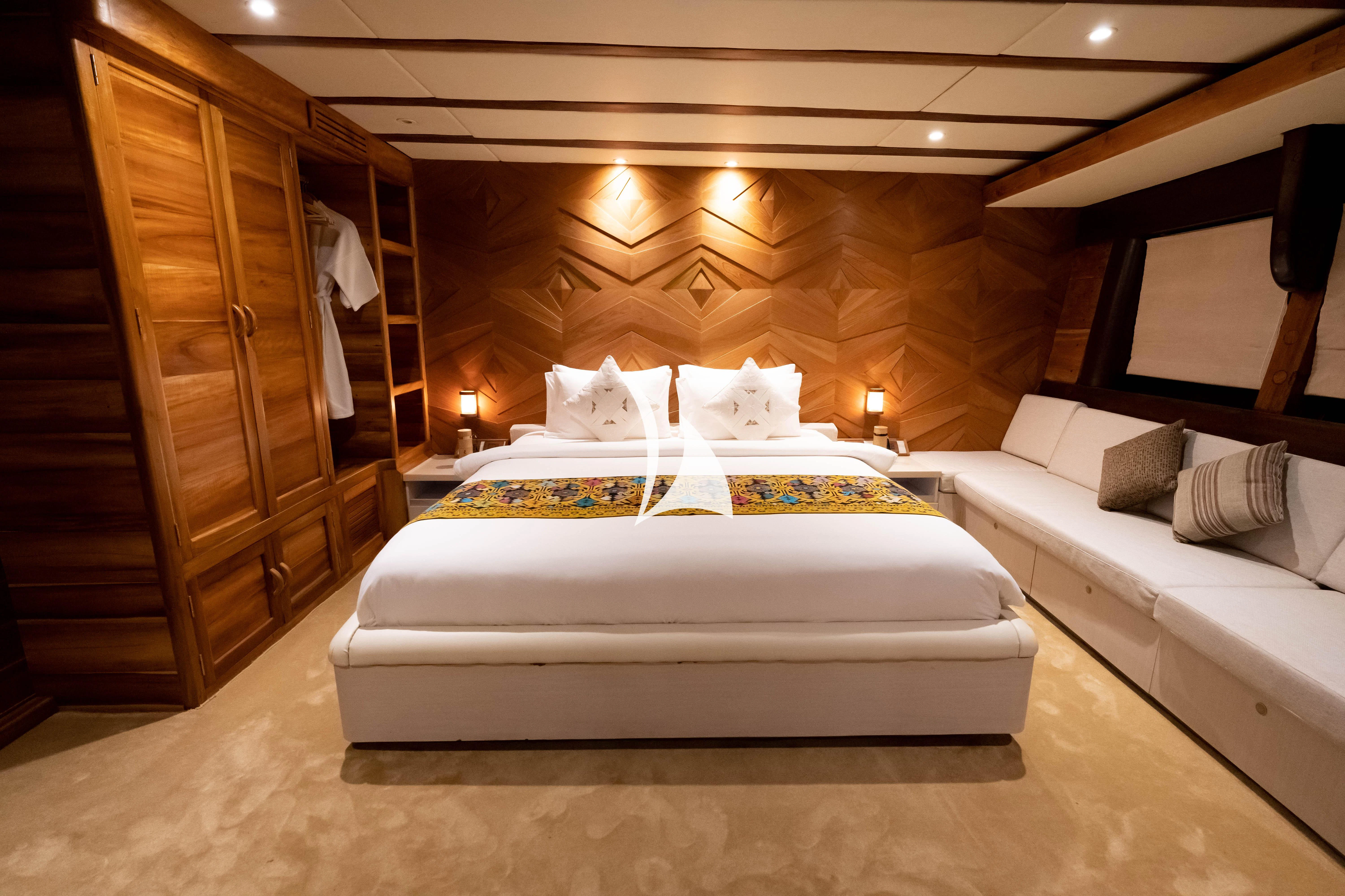a bedroom with a bed and a wood cabinet aboard LAMIMA Yacht for Sale