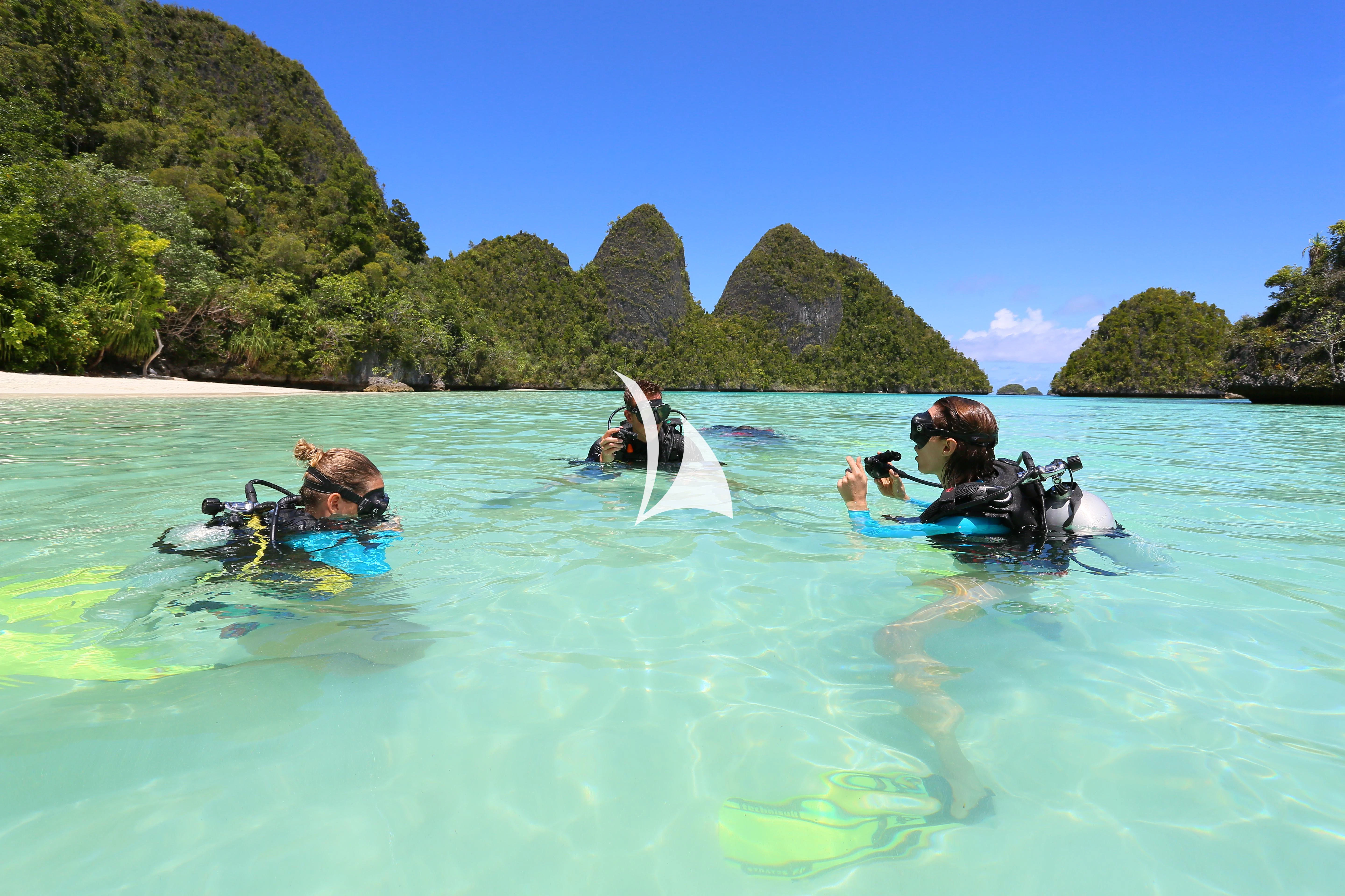 people swimming in a body of water with Phi Phi Islands in the background aboard LAMIMA Yacht for Sale