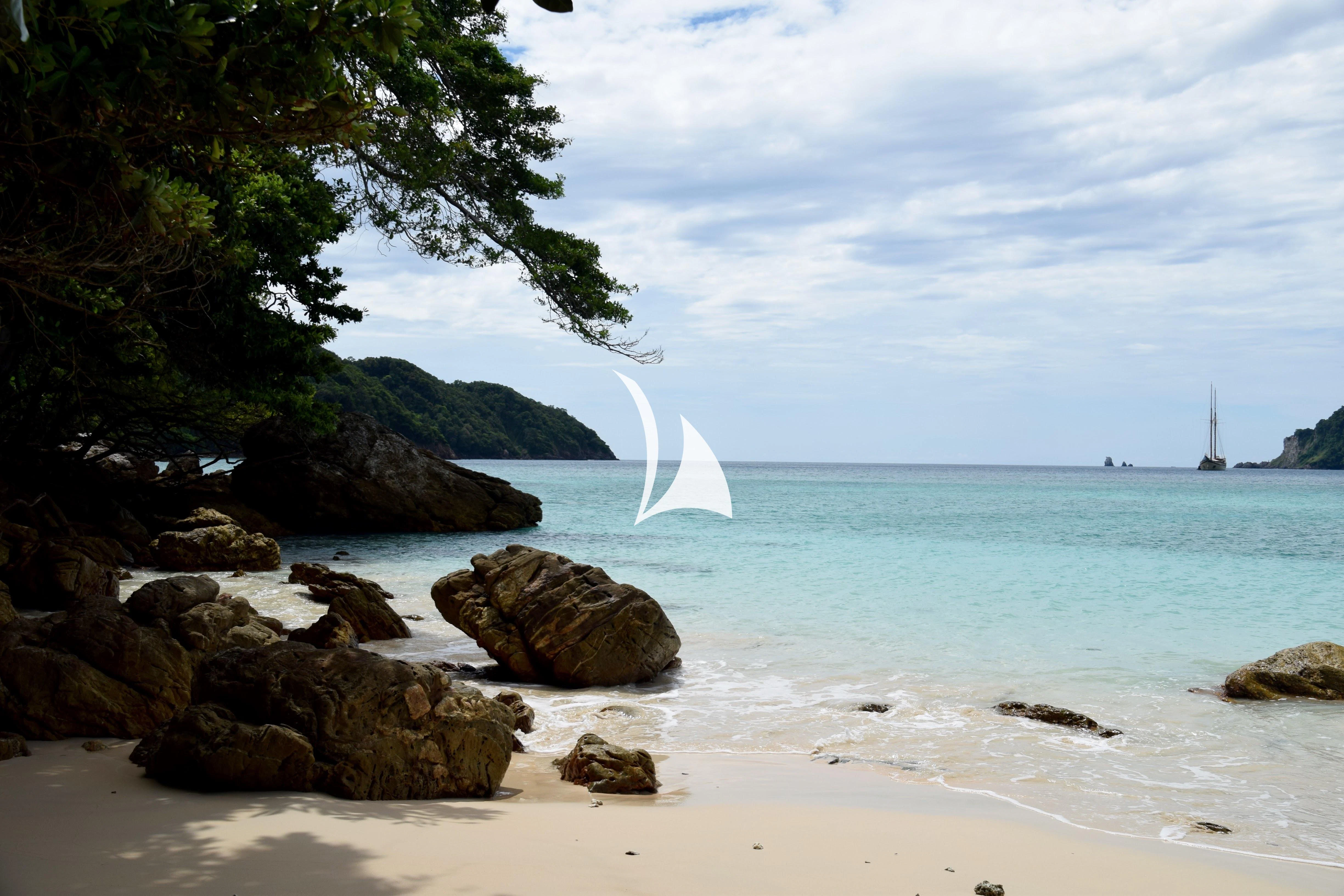 a beach with a sailboat aboard LAMIMA Yacht for Sale
