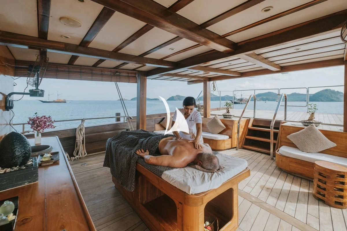 a man lying on a couch with a woman on the back of him aboard LAMIMA Yacht for Sale