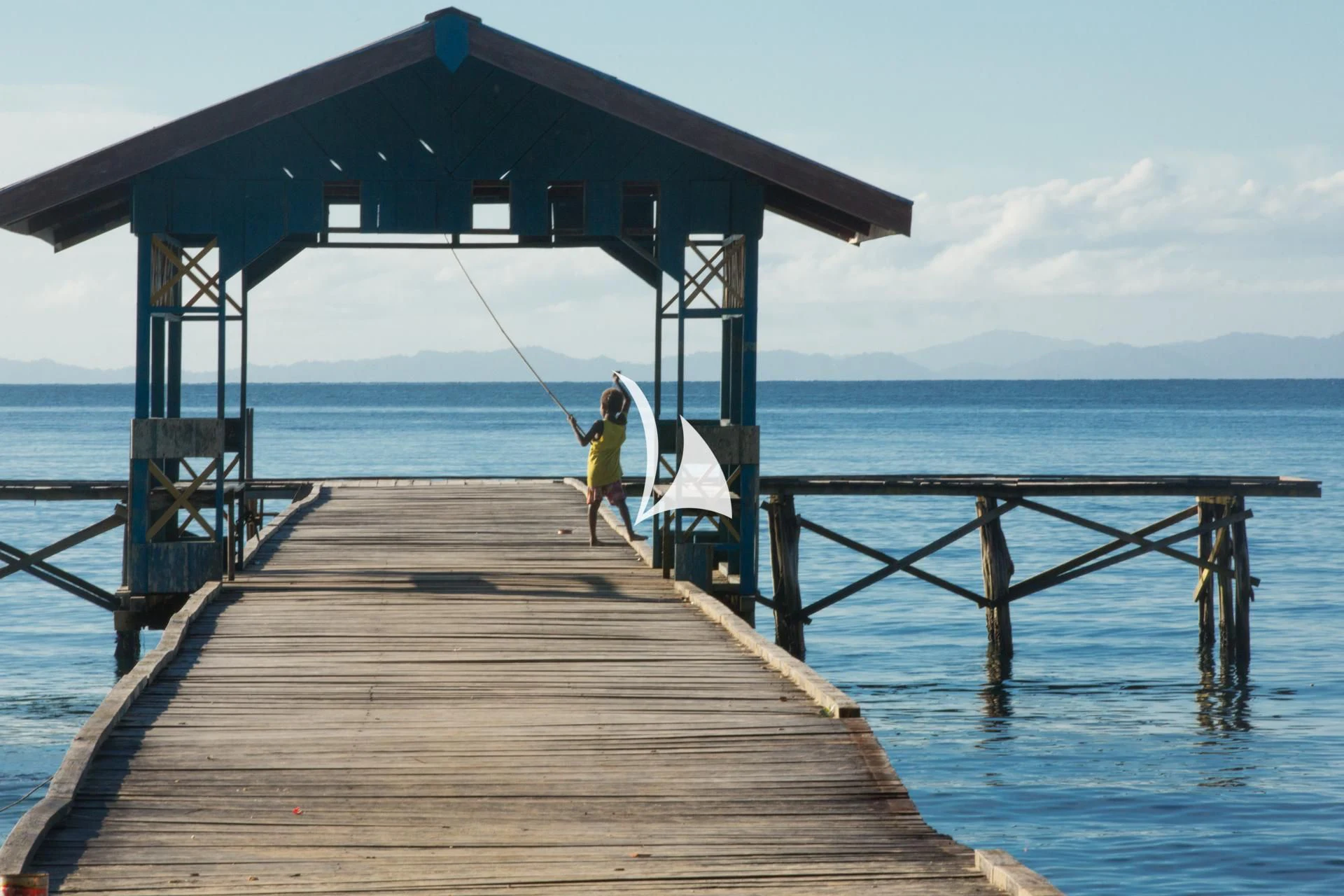 a person walking on a dock with a surfboard aboard LAMIMA Yacht for Sale