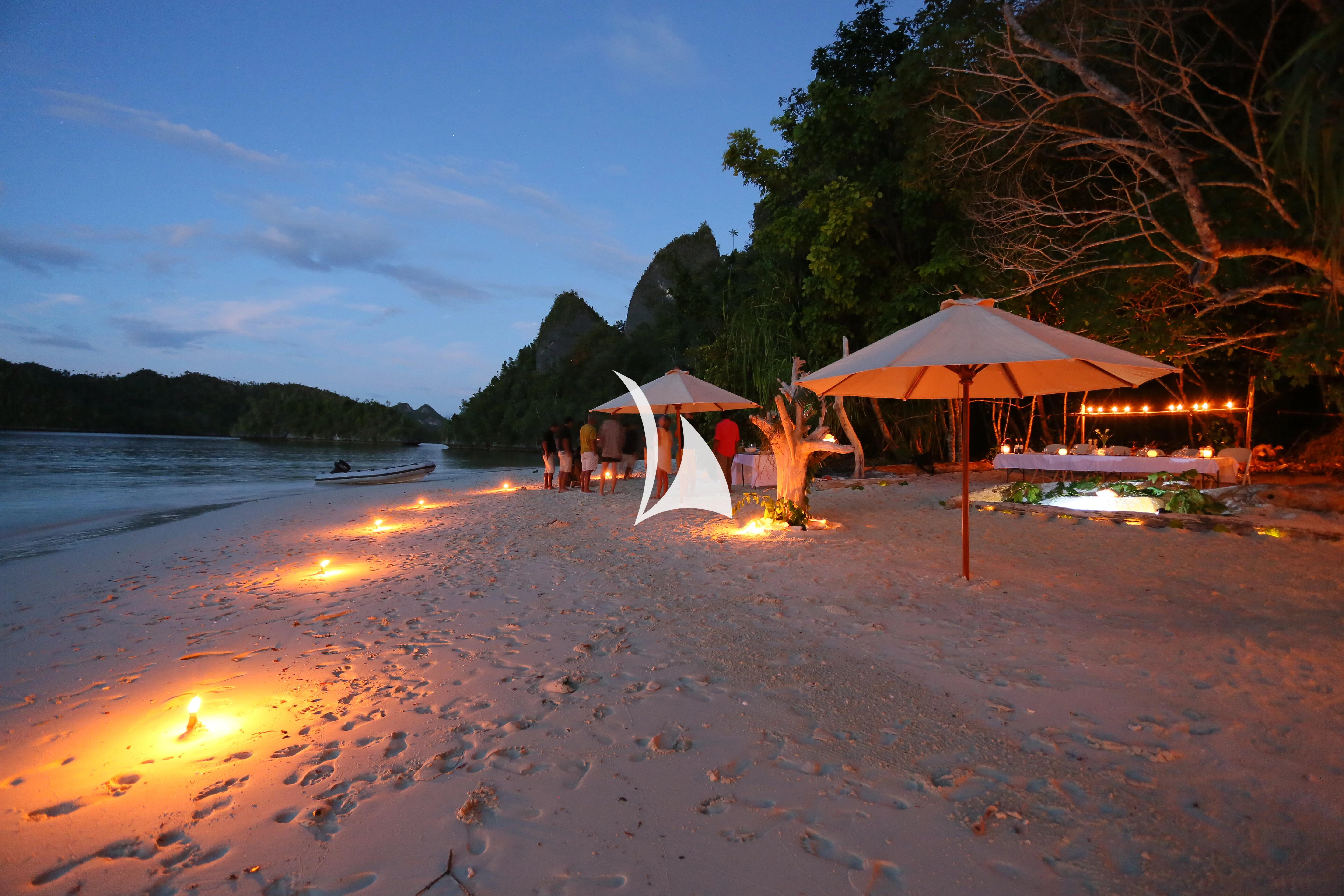 a beach with tents and people aboard LAMIMA Yacht for Sale
