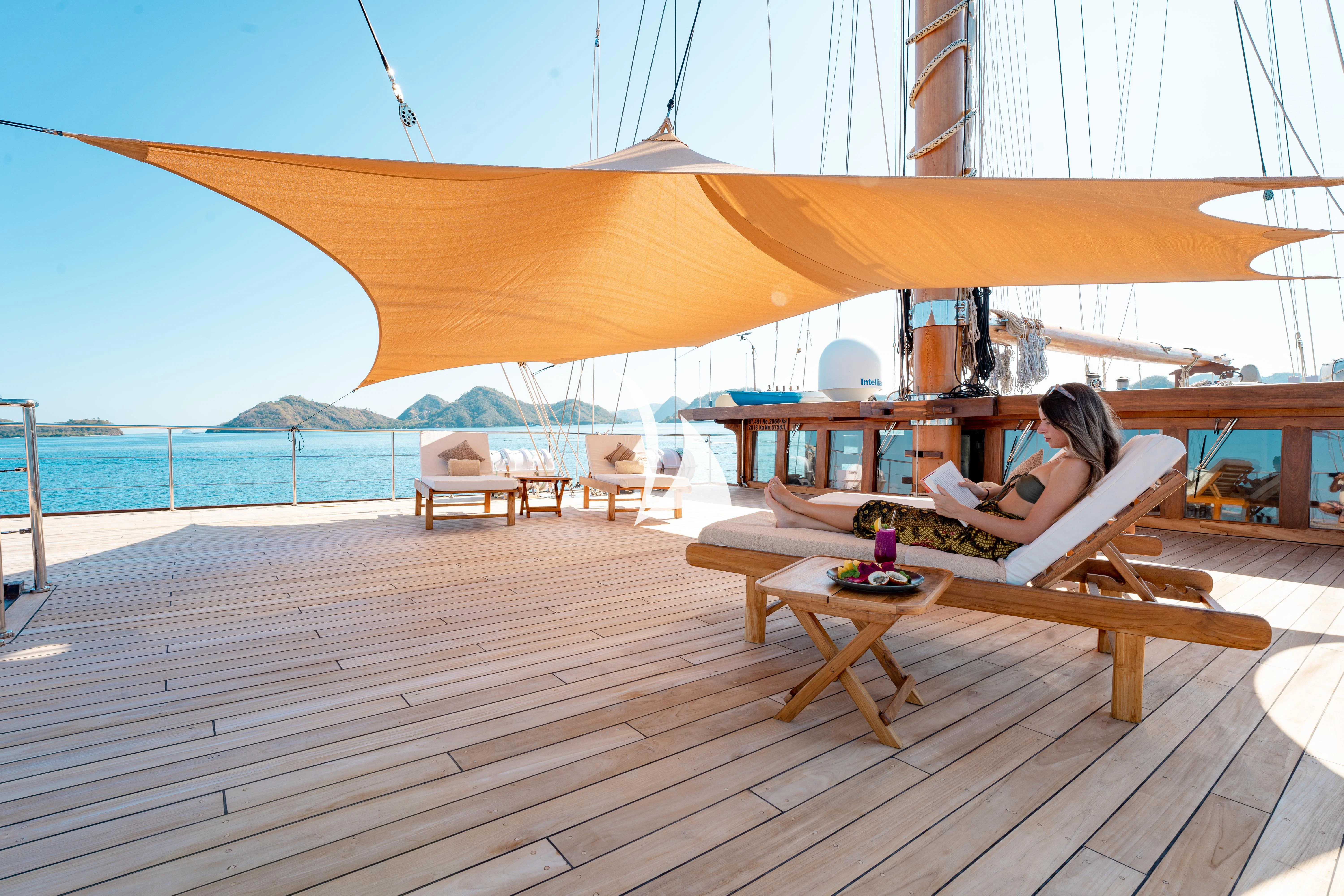 a person sitting on a chair on a deck with a large body of water in the background aboard LAMIMA Yacht for Sale