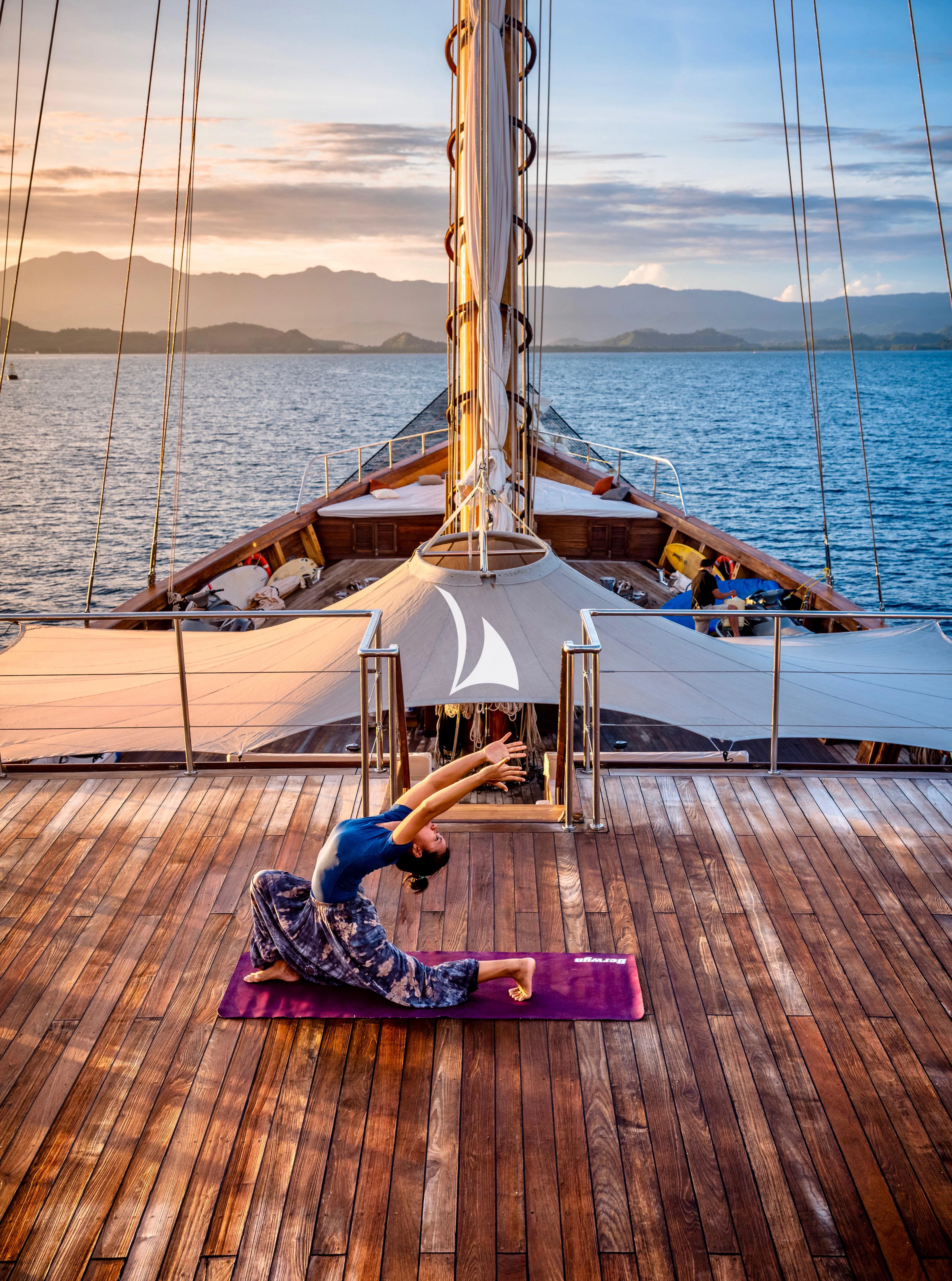 a person doing a handstand on a deck by a large ship aboard LAMIMA Yacht for Sale