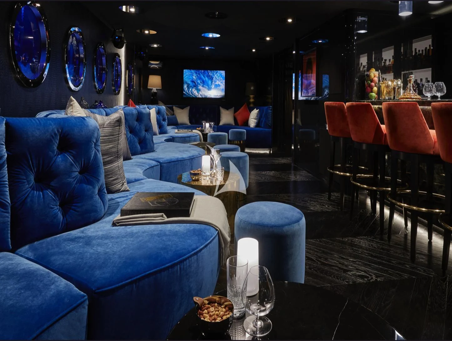 a room with blue couches and a table with chairs and a television aboard IJE Yacht for Sale