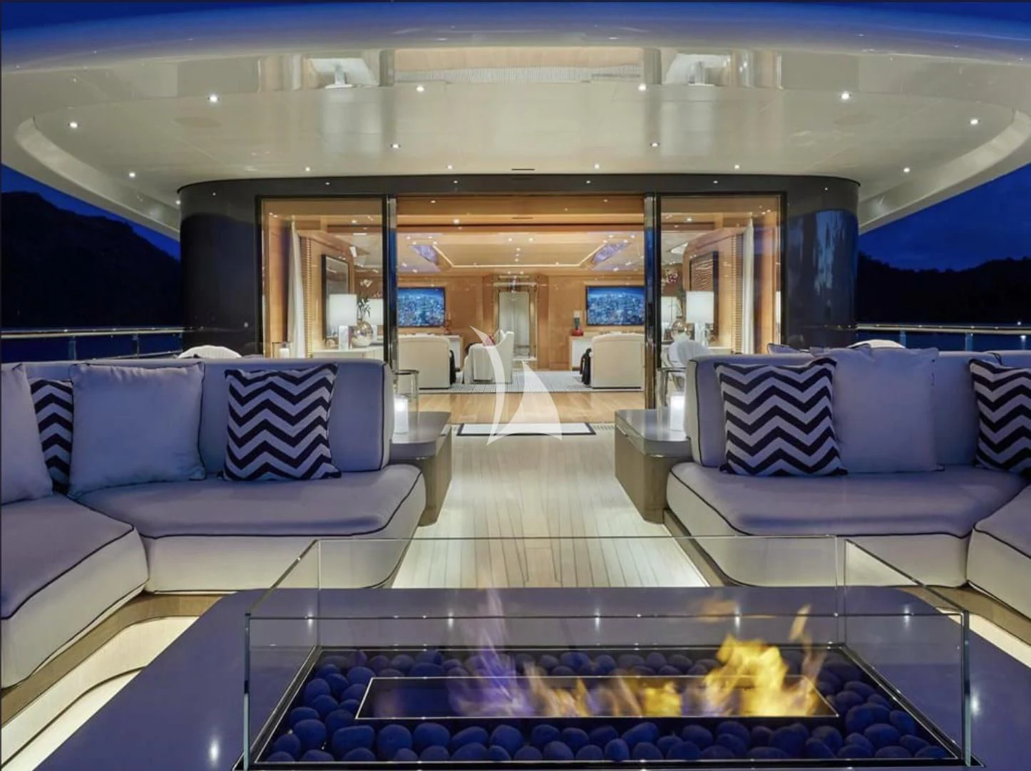 a large living room with a large glass table and a fireplace aboard IJE Yacht for Sale