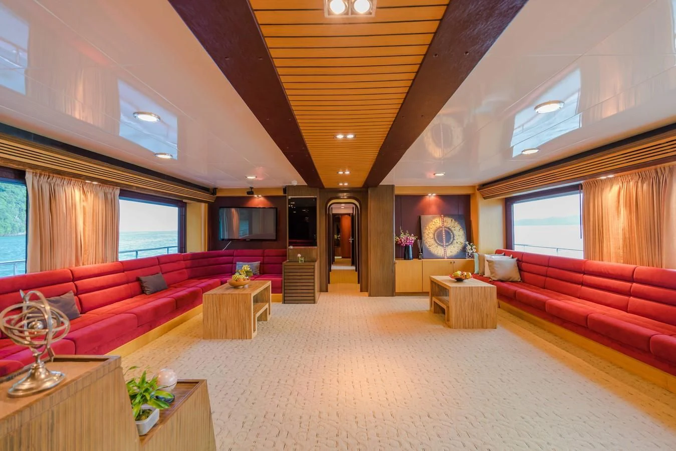 a large living room with red couches and a fireplace aboard PHATSARA Yacht for Sale