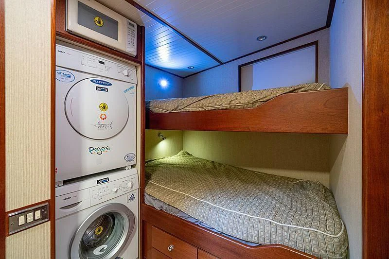 a small bed next to a washer and dryer aboard NIRVANA Yacht for Sale