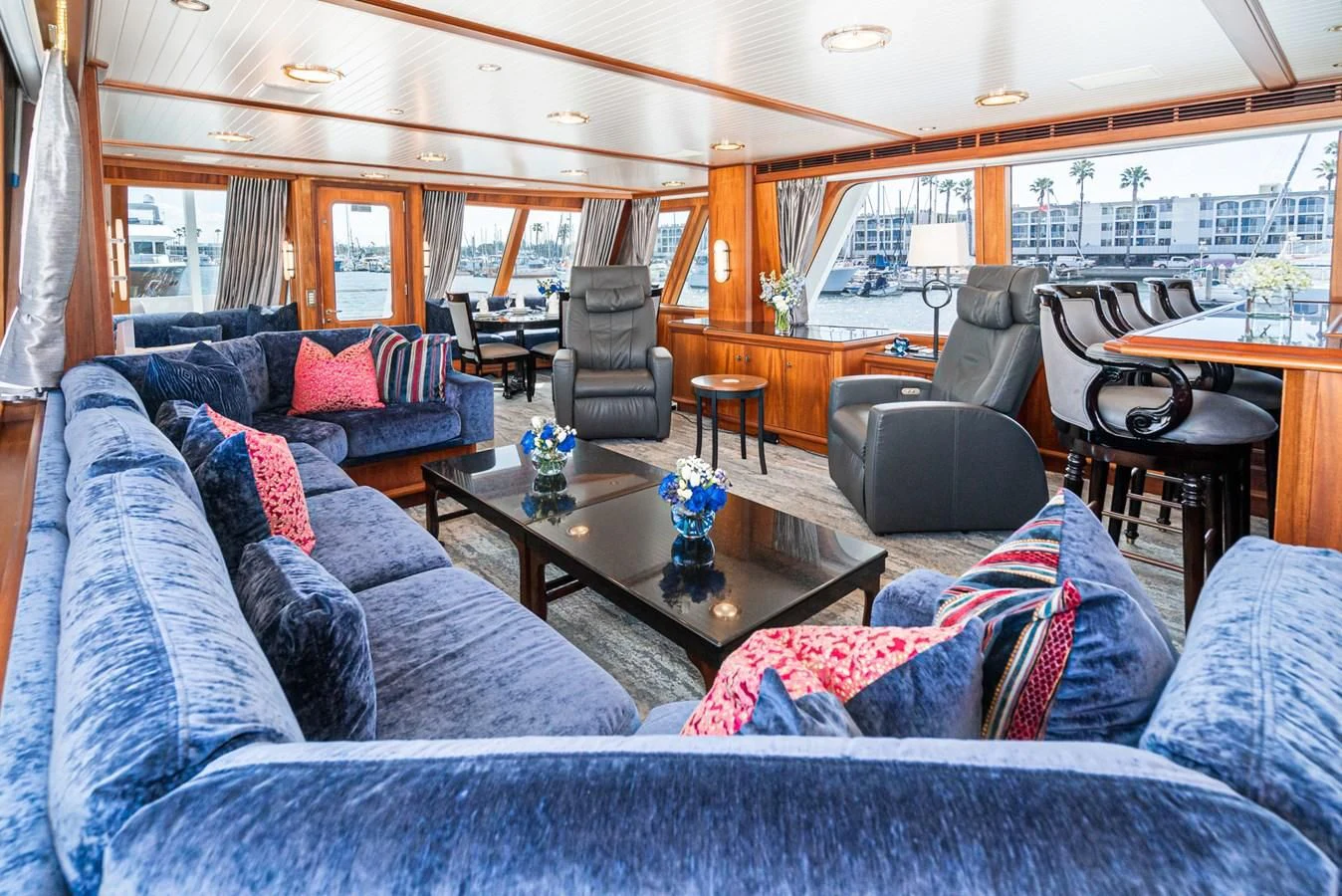 a living room with a large blue couch and a large window aboard NIRVANA Yacht for Sale