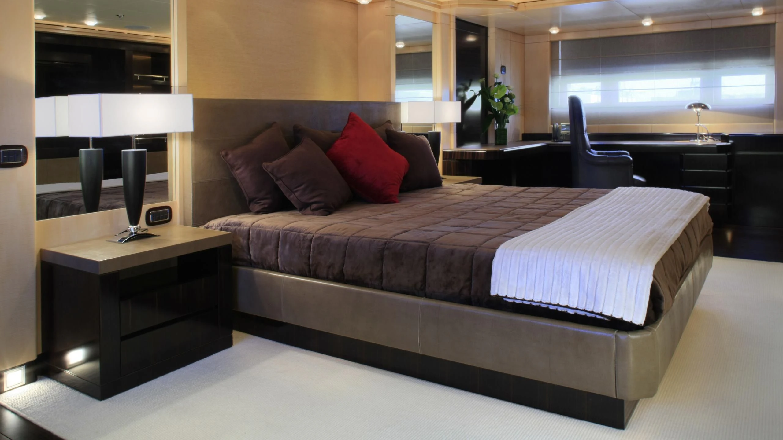 a bed with a red and white pillow on it aboard MUZA Yacht for Sale