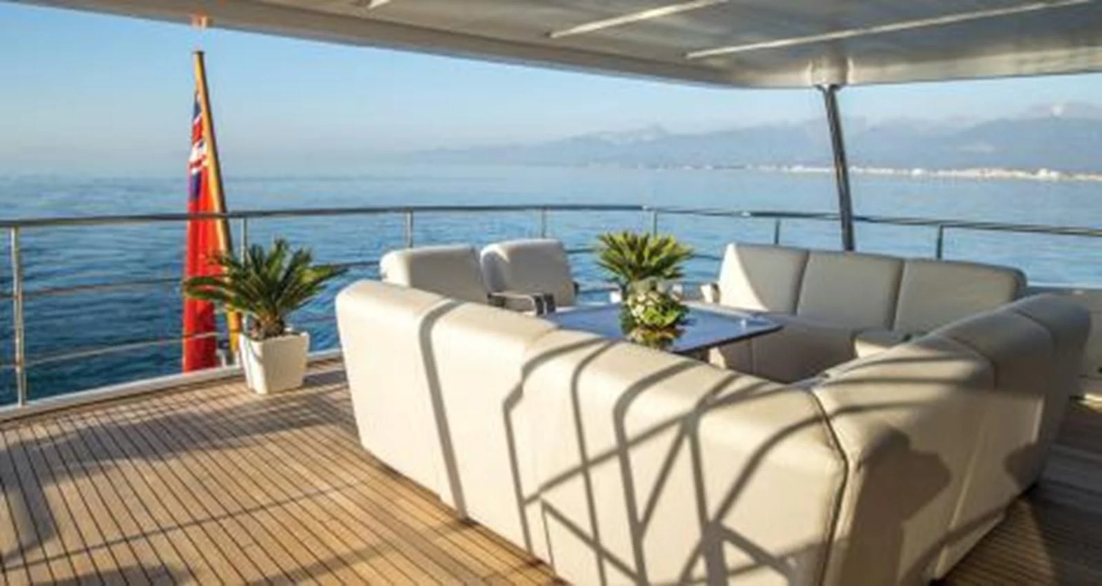 a deck with a large body of water and a large red flag aboard NELA Yacht for Charter