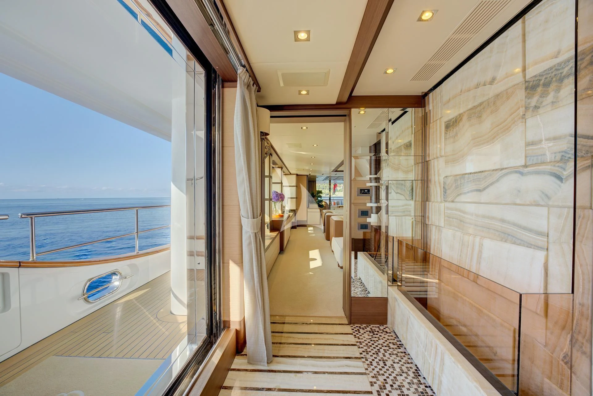 a long hallway with glass walls aboard NELA Yacht for Charter