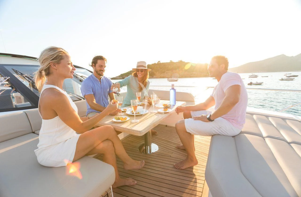 a group of people sitting around a table with food and drinks on it aboard STRATEGIC DREAMS Yacht for Sale