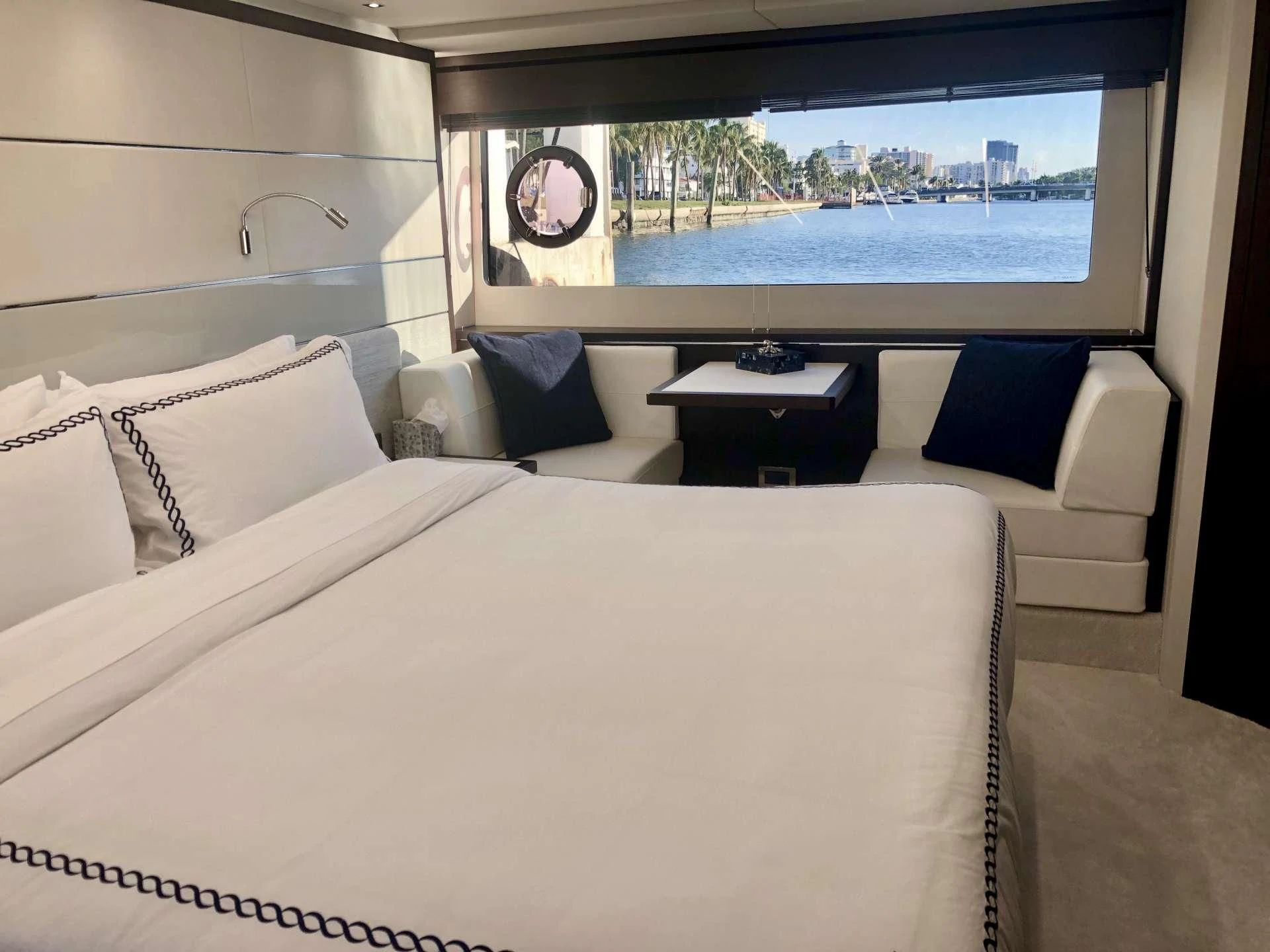 a bed with a white sheet and pillows in a room with a large window aboard STRATEGIC DREAMS Yacht for Sale